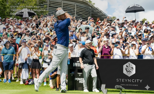 A professional golfer teeing off with a full gallery crowd at the LIV Golf South Africa tournament at Steyn City, featuring a 'Steyn City Parkland Residence' sign in the foreground